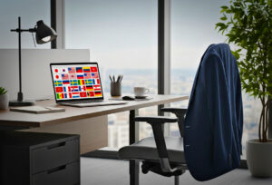 Laptop showing flags from multiple countries on a sleek office desk, representing cultural diversity and global management styles.